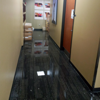 A hallway of an office building with standing water on the floor.